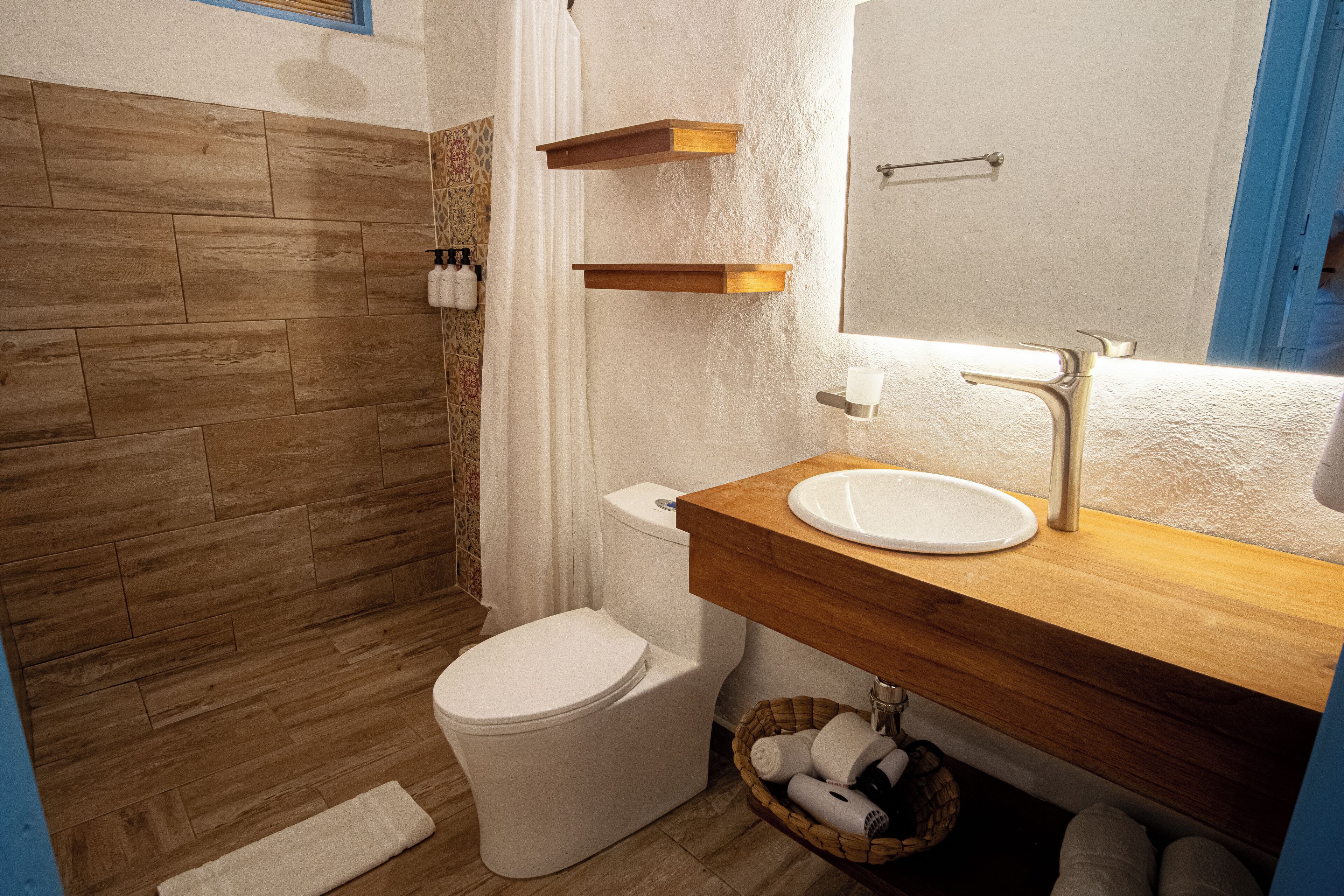 A bathroom with a wooden vanity, white sink, and a shower area.
