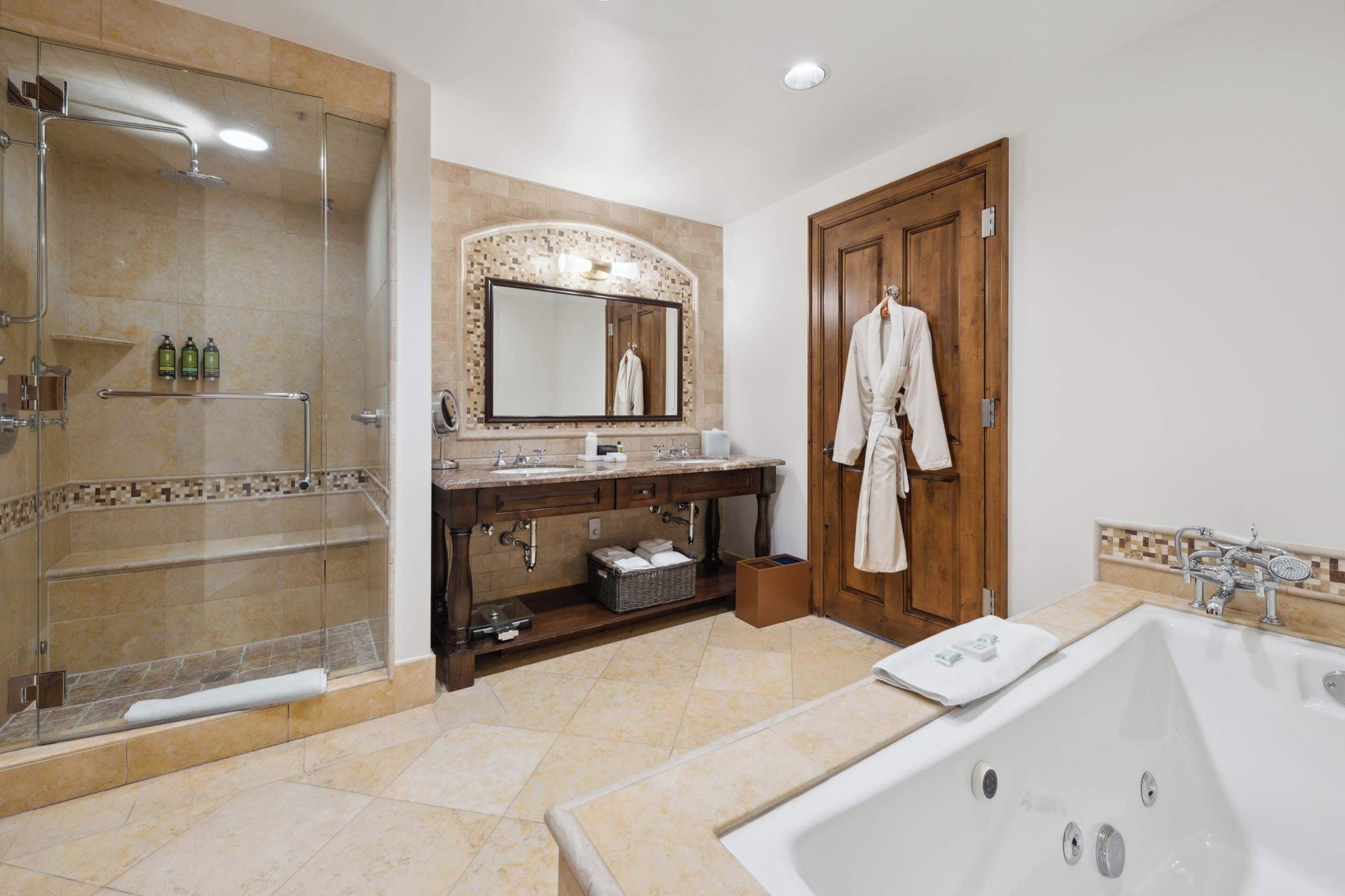 Une salle de bain moderne dotée d’une douche à parois de verre, d’une grande baignoire et d’un meuble-lavabo avec un miroir et un évier.