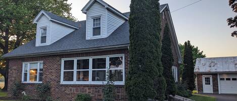 A two-story house with a brick facade, white windows, and a chimney.