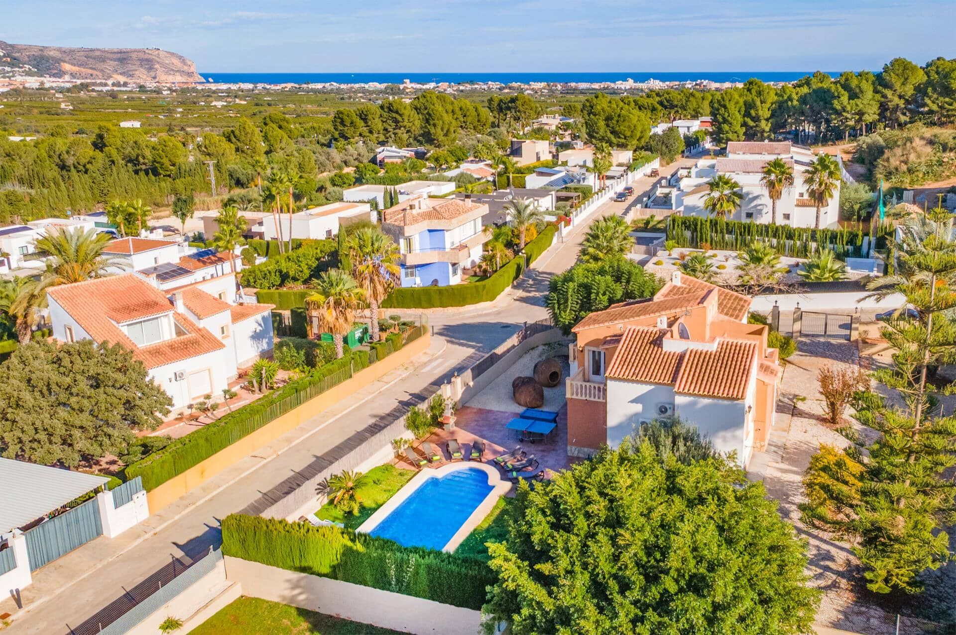 A residential area with houses, a swimming pool, and a view of the sea.