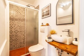 Een badkamer met douche, toilet, wastafel en een spiegel.