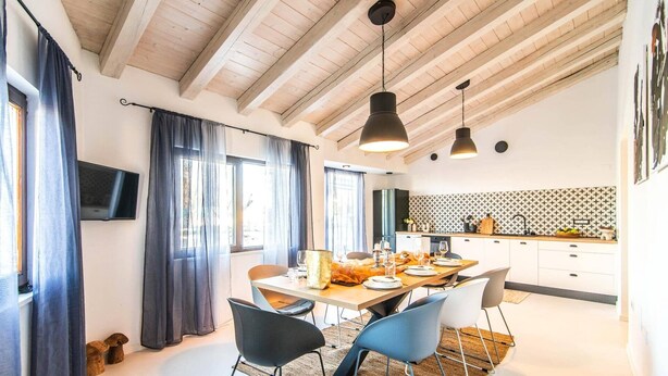 Une cuisine moderne avec des meubles blancs, un plan de travail noir et un coin repas comprenant une table et des chaises en bois.