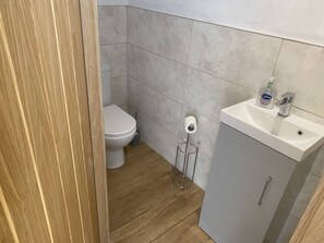 Um banheiro pequeno com vaso sanitário, pia e suporte para papel higiênico.