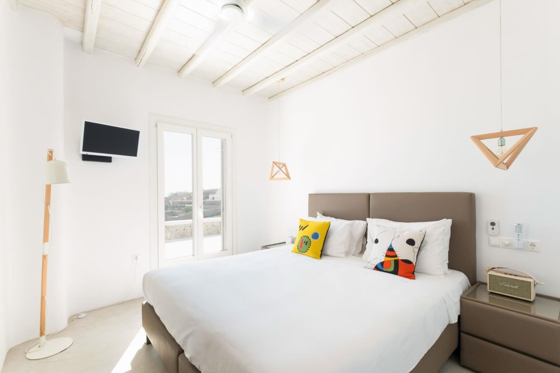 Une chambre à coucher avec un lit, une table de chevet, une lampe, une télévision et une fenêtre donnant sur un beau paysage.