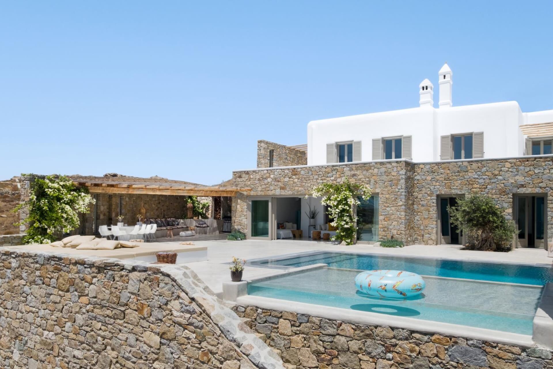 Uma villa moderna com fachada de pedra, piscina e área de estar ao ar livre.