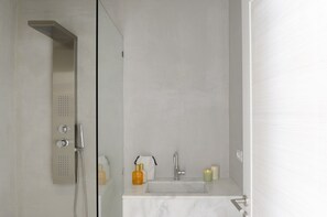 A modern bathroom with a glass-enclosed shower, a marble sink, and toiletries on the counter. - Inviting 7-bed Villa in Mikonos - Villa Jackie (Mykonos)