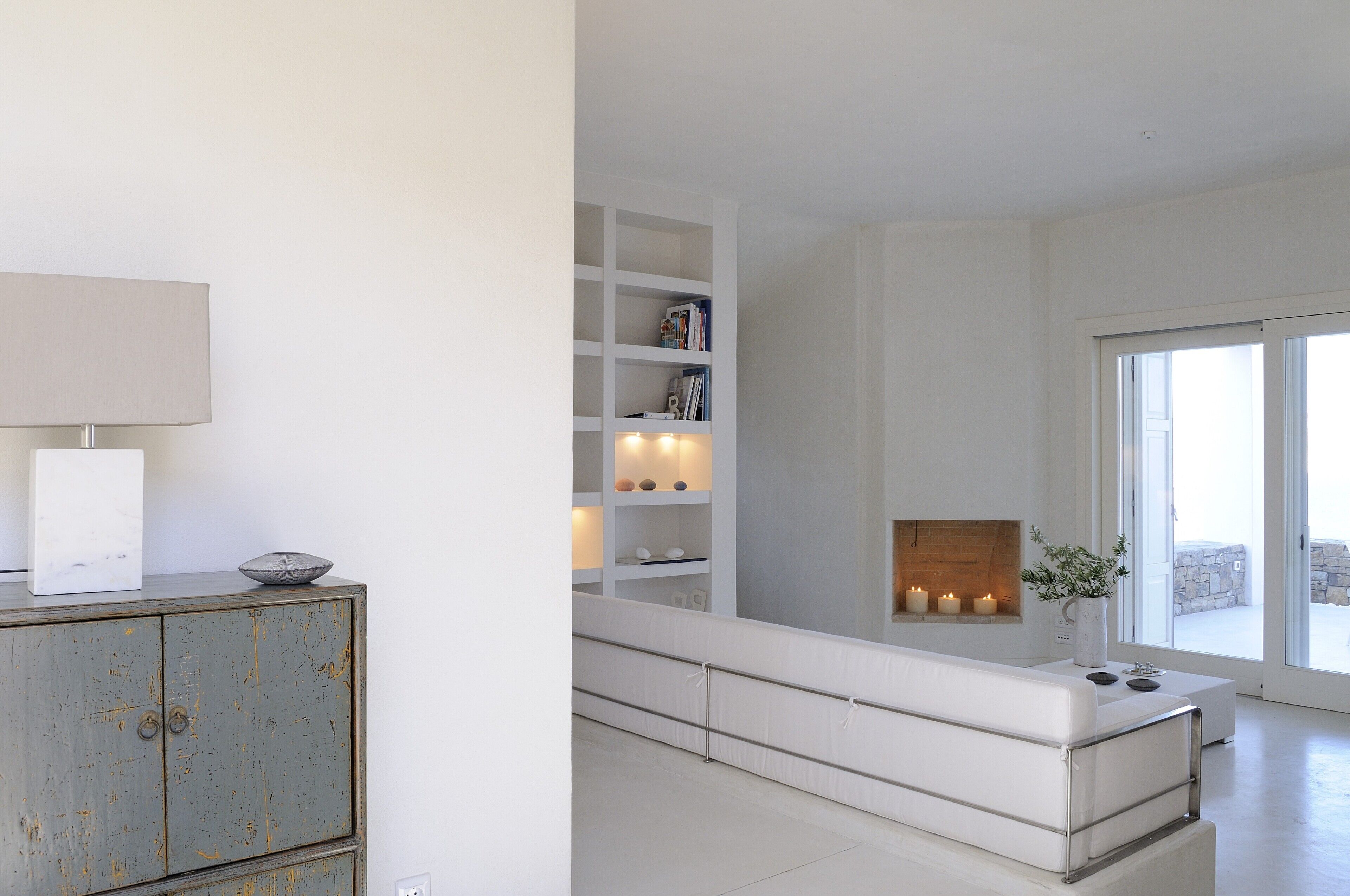 En moderne stue med en hvid sofa, en reol og en pejs.