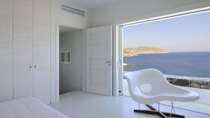 Une chambre moderne dotée d’une grande fenêtre donnant sur une vue imprenable sur la côte.