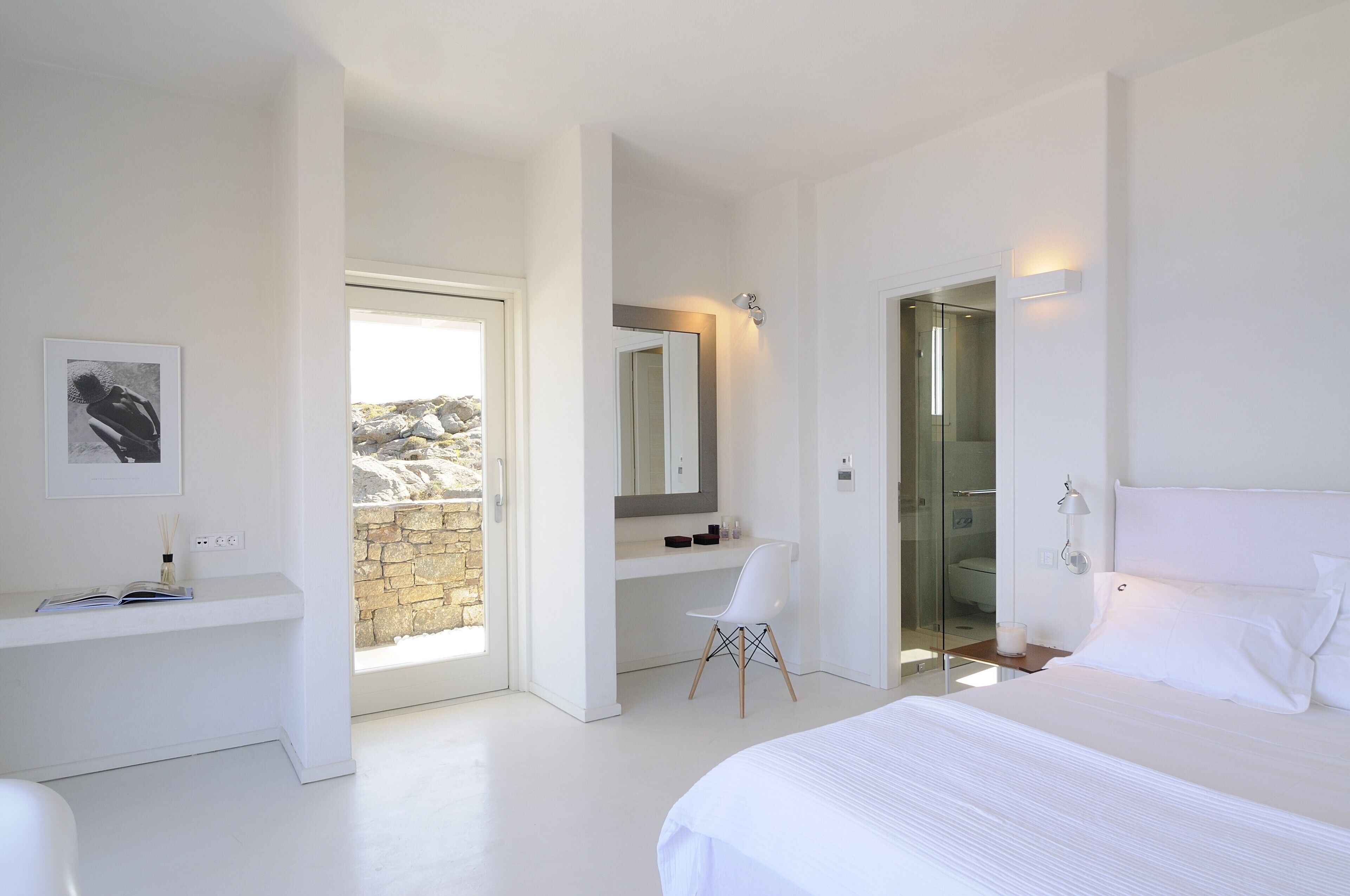 Une chambre moderne avec un grand lit, un bureau blanc, une chaise, un miroir et un espace douche.