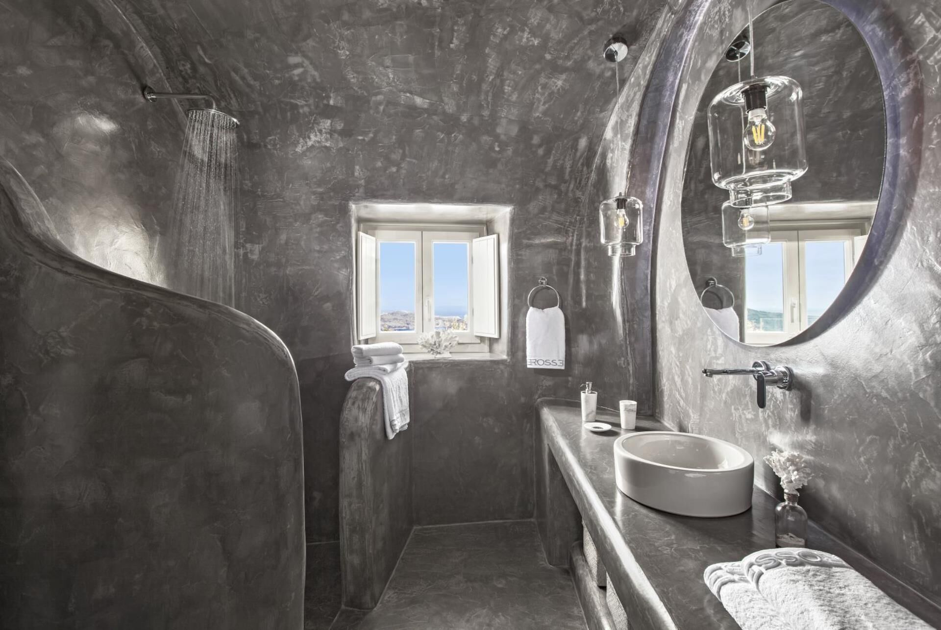 A modern bathroom with a large mirror, a bathtub, a sink, and a window providing a view.