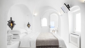 Une chambre à coucher moderne et minimaliste, avec un grand lit, des murs blancs et des portes en arc de cercle.