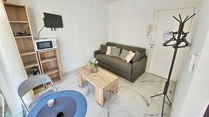 A living room with a sofa, coffee table, TV, and a bookshelf.