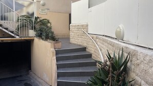 A set of outdoor stairs leading to a building entrance, with a sign reading "Villa Thais" and a security camera above the stairs.