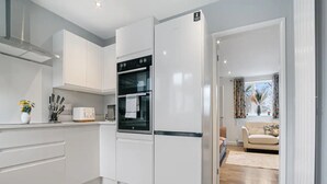 Una cucina moderna con mobili bianchi, forno integrato e frigorifero.