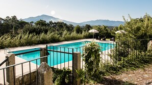 A swimming pool with a stone border and metal railing, surrounded by lush greenery and a mountainous backdrop. - Quinta do Convento Val Pereiras (Ponte de Lima)