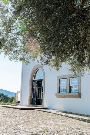 A building with a stone facade, an arched entrance, and a window. - Quinta do Convento Val Pereiras (Ponte de Lima)