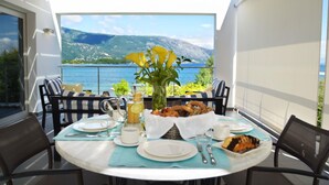 A round table set for breakfast with a view of a lake and mountains.