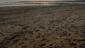 Ein Strand mit Fußspuren und ein paar Personen in der Ferne.