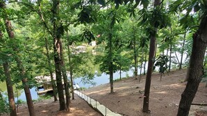 Una terraza de madera con barandilla metálica que da a un lago, rodeada de árboles.