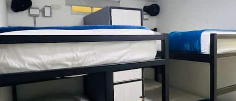 A bunk bed room with a white ceiling, a visible light fixture, and a small window with a blind.