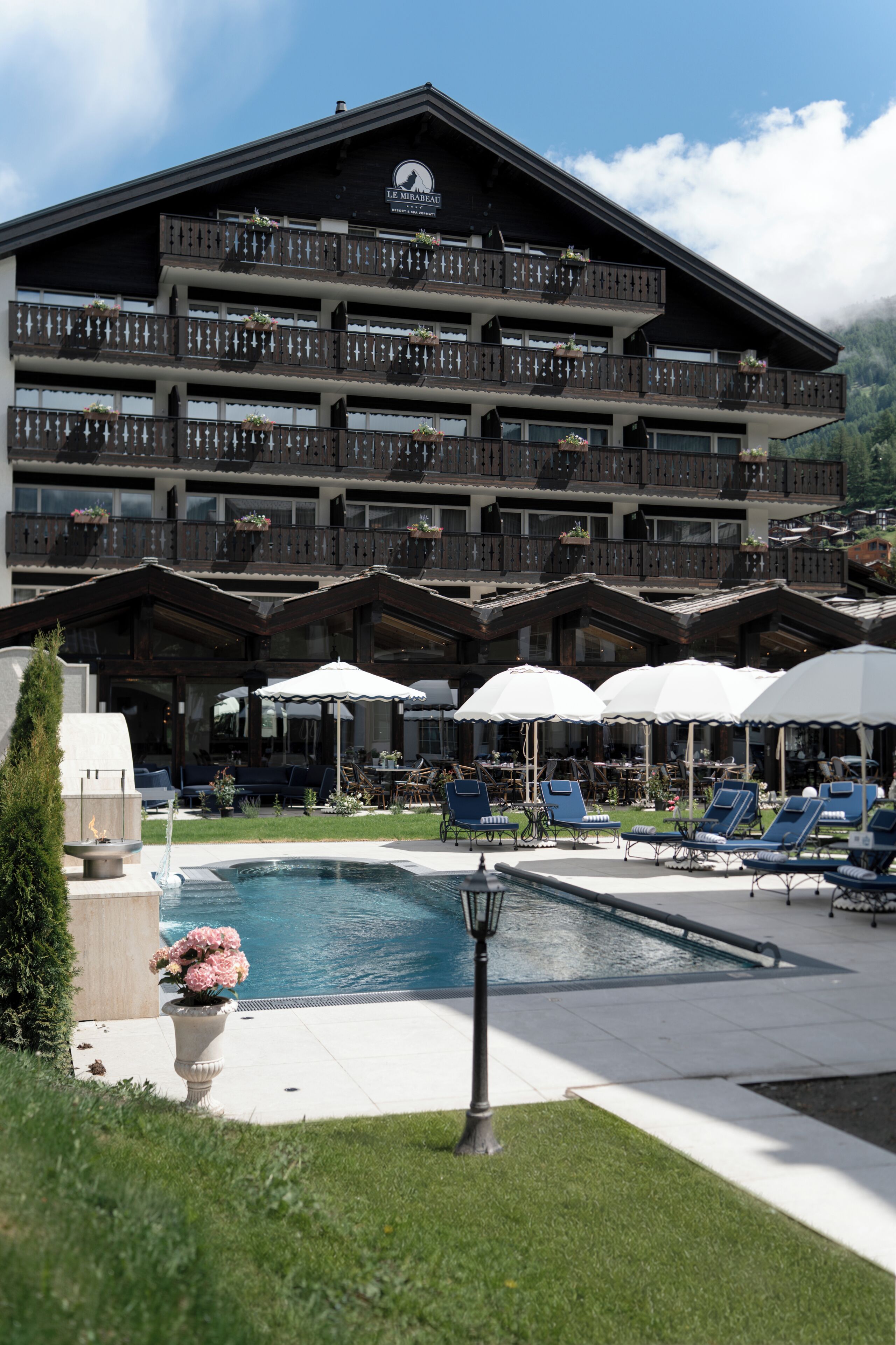 Ein mehrstöckiges Hotel mit Balkonen, einem Schwimmbad und Außenbereichen mit Sitzgelegenheiten.