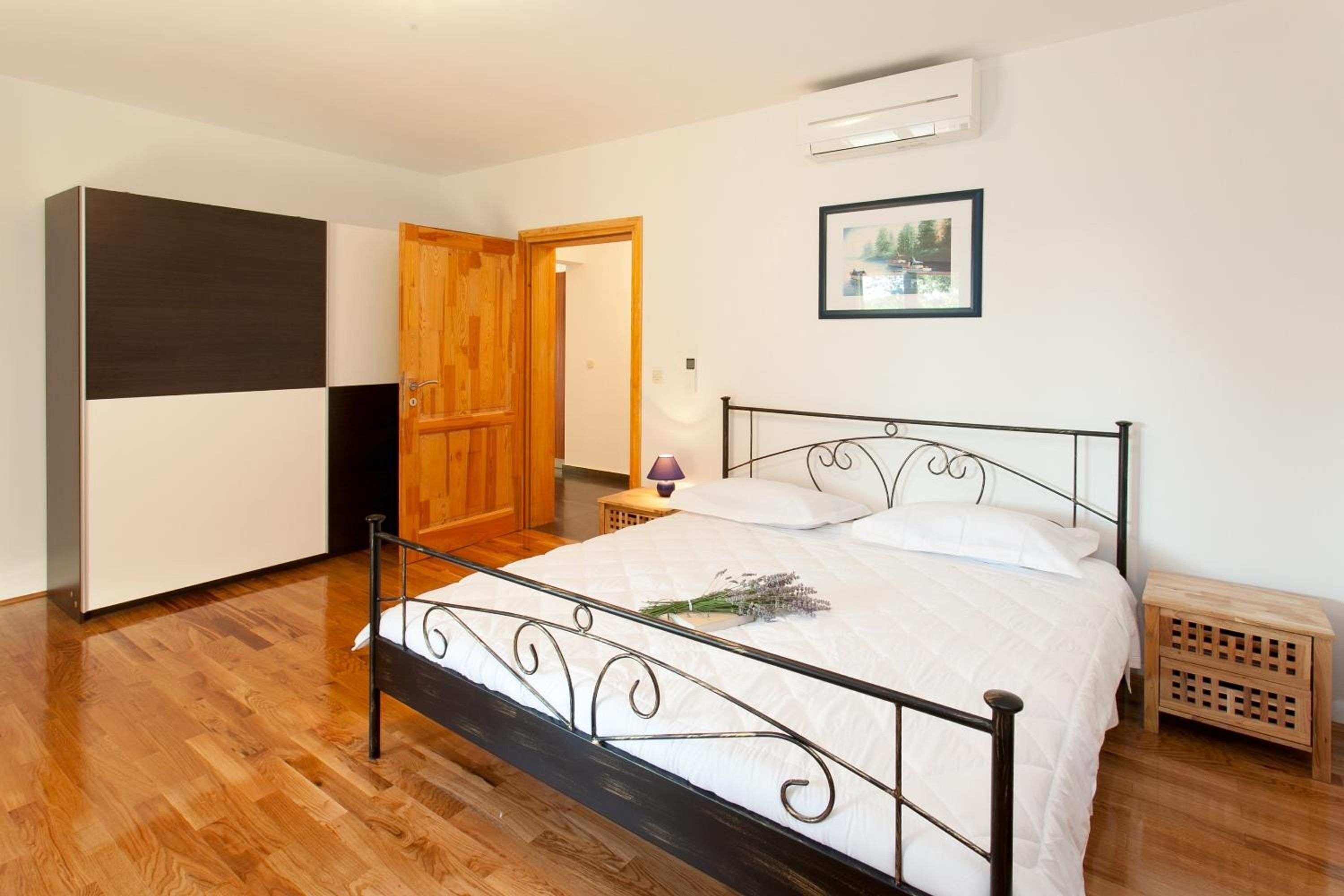 Een slaapkamer met een bed, een houten garderobe en een deur naar een andere kamer.