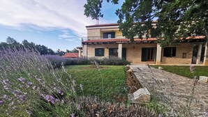 A two-story house with a stone facade and red-tiled roof, surrounded by a well-maintained garden with lavender and other plants. - Villa Paradiso Zadarvillas (Policnik)