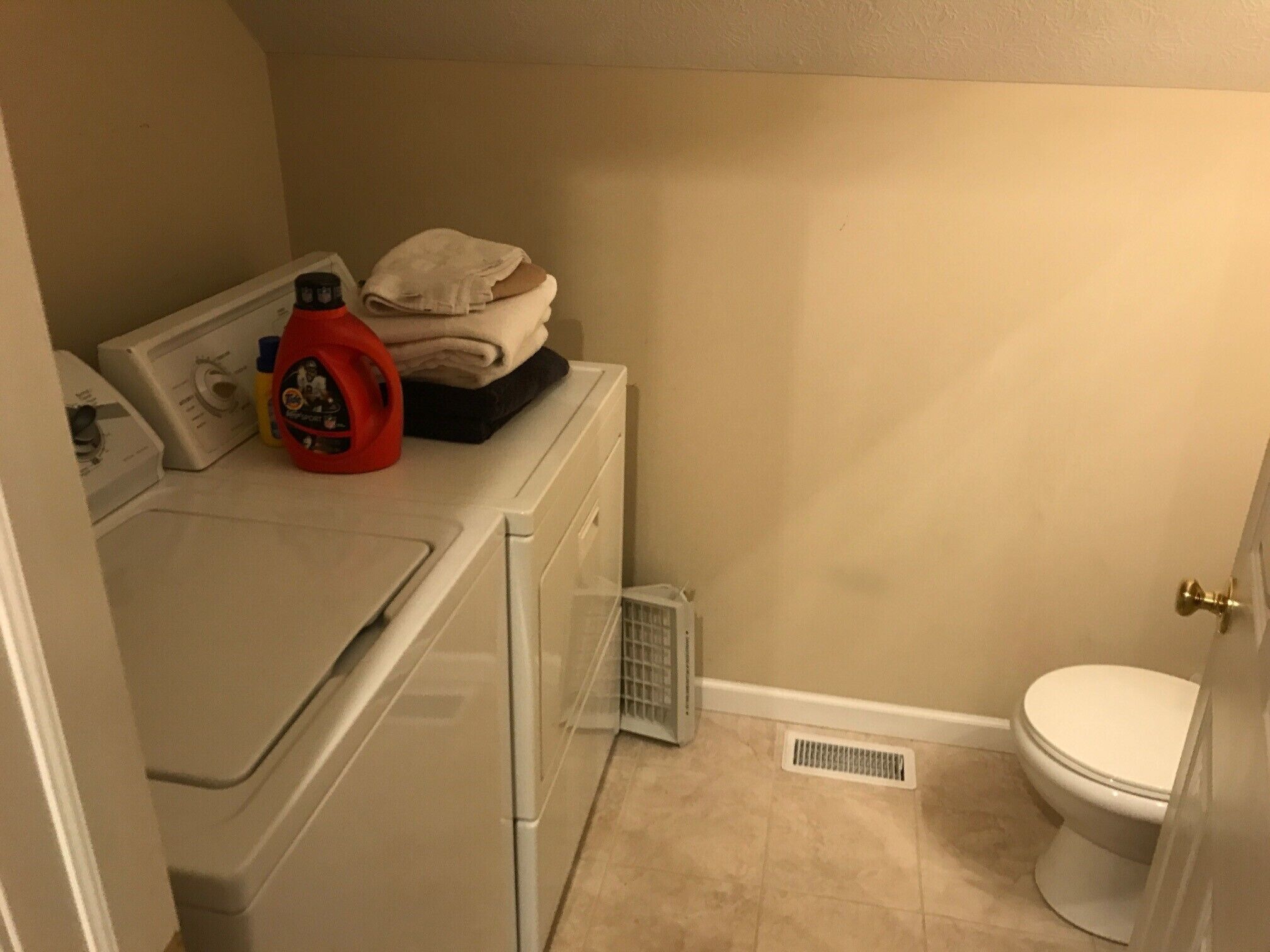 A compact laundry area with a washing machine, dryer, and stacked towels.