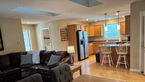 A modern living room with a leather sofa, a dining table, and a kitchen area with wooden cabinets and a refrigerator. - Bloomington hideaway, 10 min from downtown, catch some fish in private pond. (Bloomington)