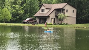 A house by a lake with a dock and a truck parked nearby. - Bloomington hideaway, 10 min from downtown, catch some fish in private pond. (Bloomington)