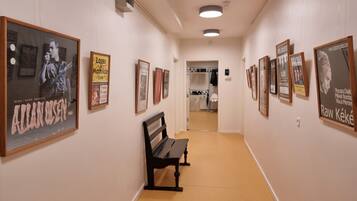A hallway with framed posters on the walls, a bench, and a closet with hanging clothes.