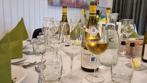 Una mesa para comer dispuesta con copas de vino, botellas y un plato de comida.
