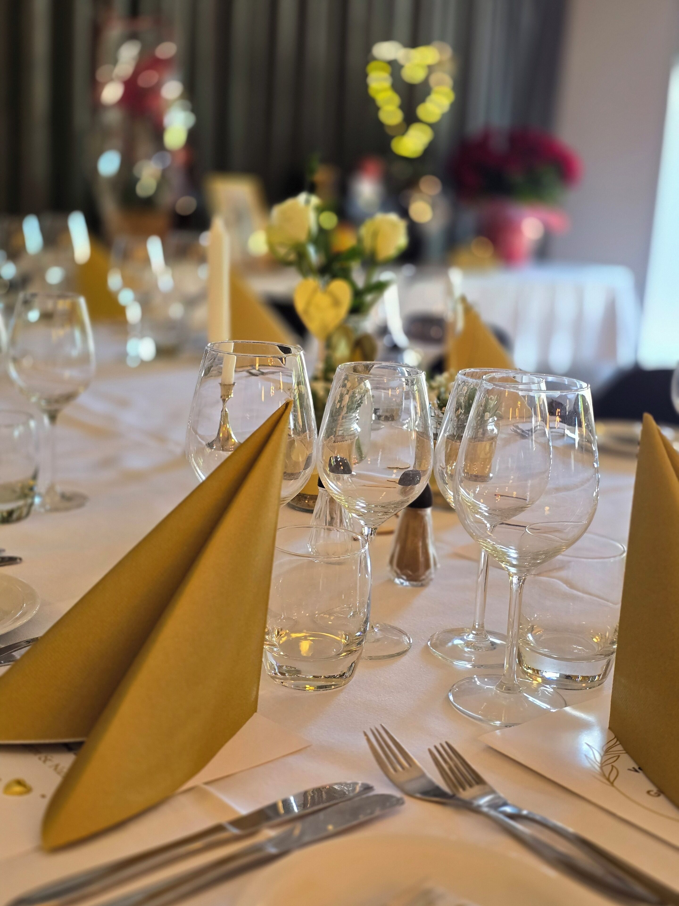 Een gedekte tafel voor een formeel diner, met glanzend servies, gouden servetten en een witte tafeldoek.
