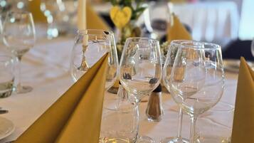 Een gedekte tafel voor een formeel diner, met glanzend servies, gouden servetten en een witte tafeldoek.