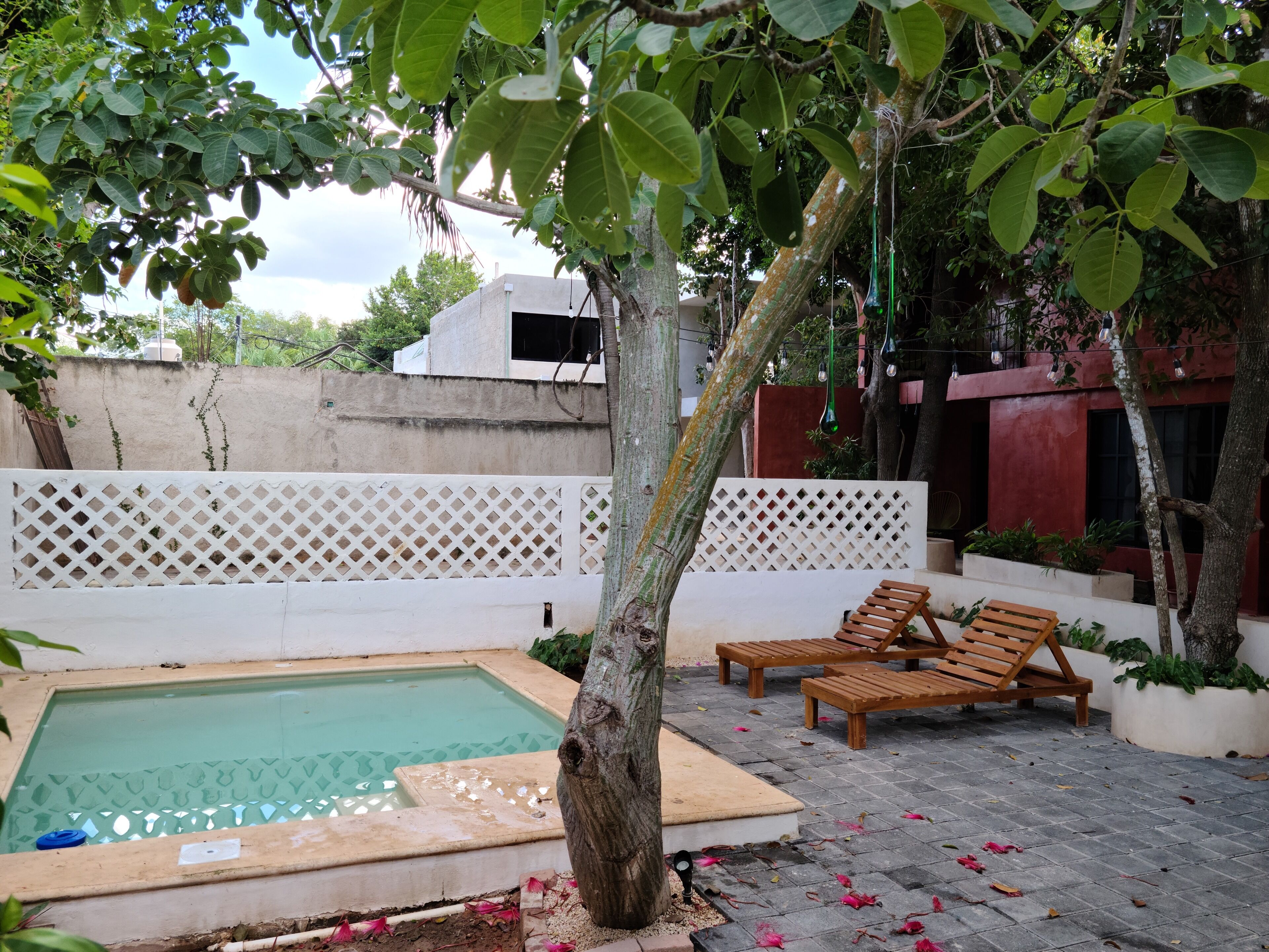 Ein Poolbereich mit Holzterrasse, Liegestühlen und einem weißen Gitterzaun.