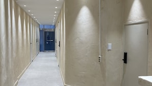 A corridor with a light-colored floor and walls, leading to a door at the end. - Hoho House (Busan)