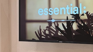 A television mounted on a wall with the word "essential" displayed on the screen. - Hoho House (Busan)