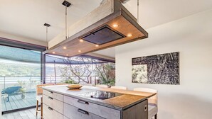 A modern kitchen with a large island, built-in appliances, and a view of the outdoors.