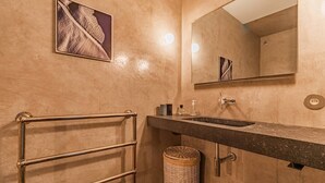 A bathroom with a towel rack, a sink, a mirror, a picture on the wall, and a wicker basket.