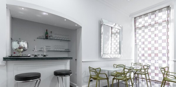 Une cuisine moderne dotée d’un coin bar, de tabourets de bar et d’une table à manger avec des chaises.