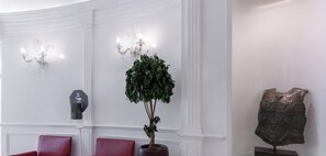 Een receptiegedeelte met een potplant, een kapstok en een decoratief metalen object.