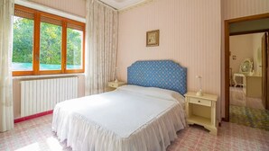 A bedroom with a large bed, a window with curtains, a bedside table, and a mirror. - Villa Mimma (Sant'Agnello)