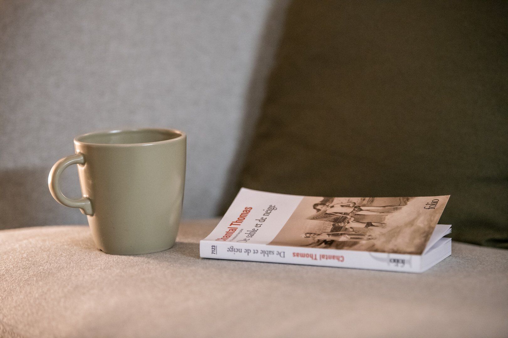 A book titled "Montal Thomas" and a mug on a textured surface.