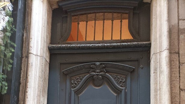 Une porte de couleur sombre, dotée d’un trou de serrure et d’un clavier pour l’ouverture à code, intégrée dans une structure en pierre.