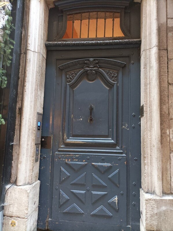 A dark-colored door with a keyhole and a keypad lock, set within a stone structure.
