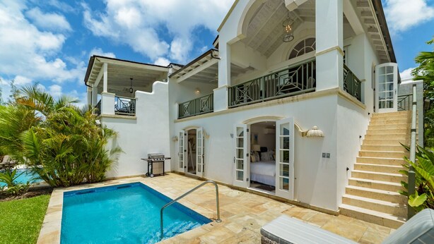 Une maison à deux étages avec une piscine, un espace salon extérieur et un escalier menant à un balcon.