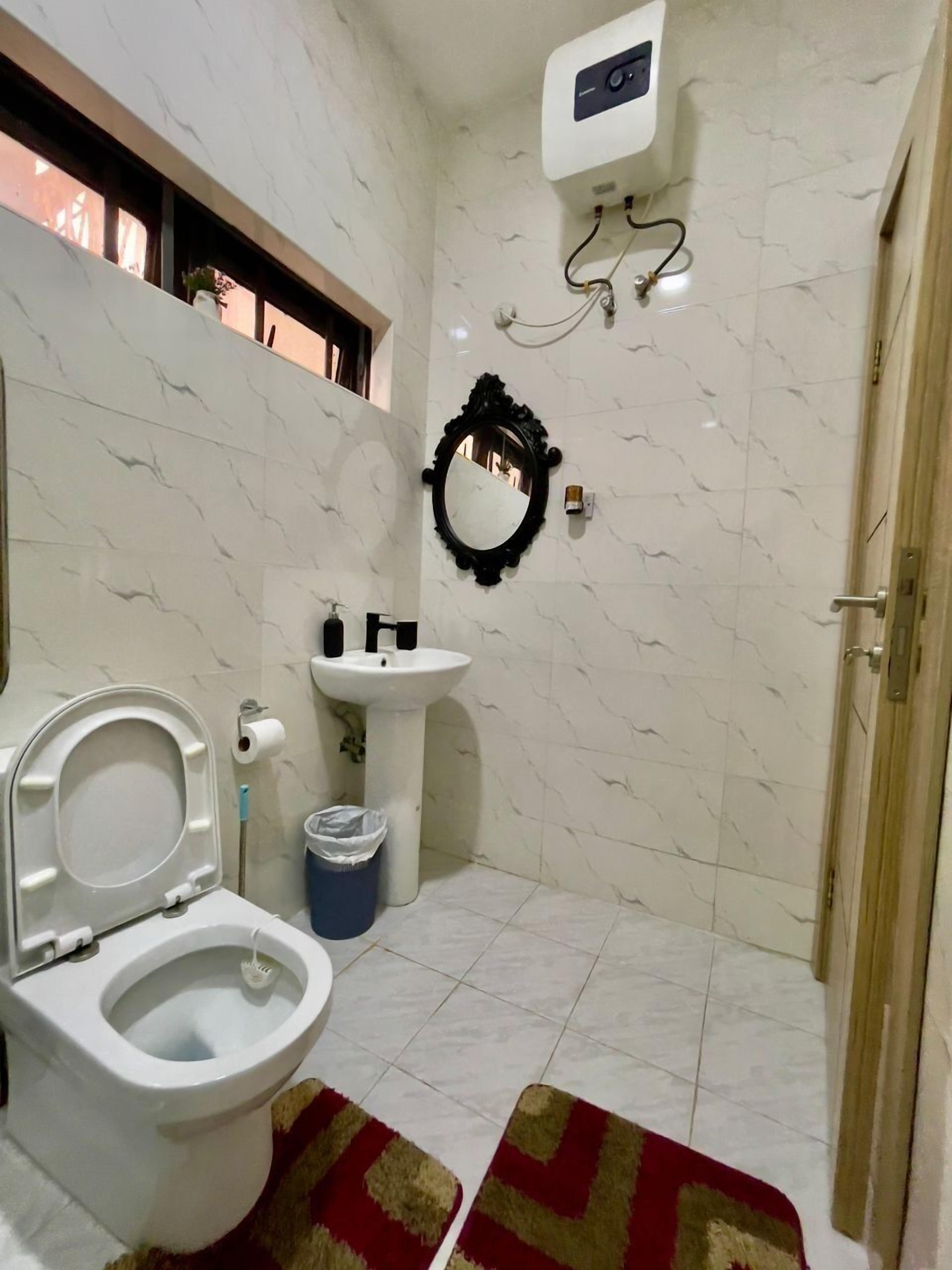 A bathroom with a toilet, sink, mirror, and shower.