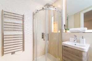Un baño moderno con ducha de vidrio, un perchero y un lavamanos con espejo.