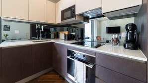 Une cuisine moderne avec des meubles de couleur sombre, un four à micro-ondes, une machine à café et une grande fenêtre.