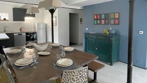 A dining area with a wooden table set for six, a modern kitchen in the background, and a blue accent wall.